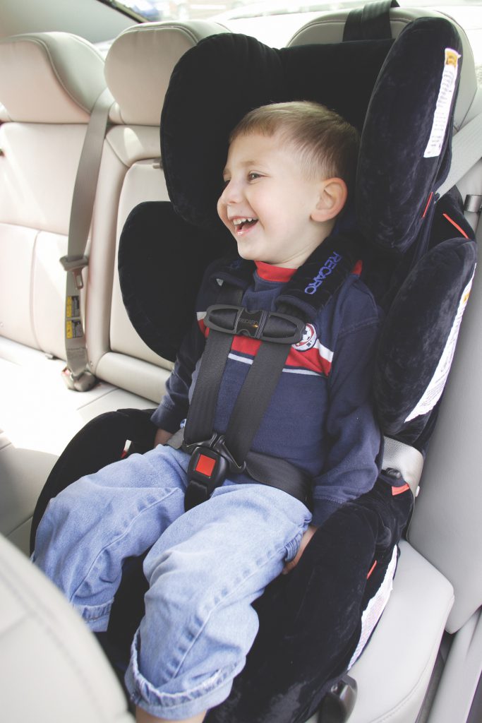 Young boy smiling sitting in car seat