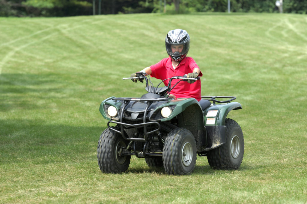 Young boy on four-wheeler, atv. All Terrain Vehicle.
